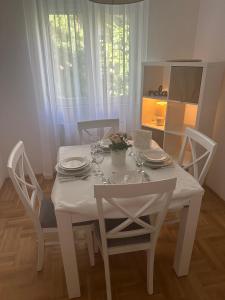 biały stół i krzesła z talerzami i okularami w obiekcie Big White M w mieście Karaburma