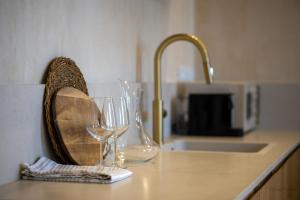 a counter with two wine glasses and a sink at Hagafen Boutique Suites in Zikhron Ya‘aqov