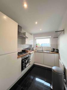 ハットフィールドにあるBeautiful Hatfield 2 Bedroom Apartment FREE Gated Parking - Modern Stylish - Business Park, Hertforshire University, St Albans, Welwyn Garden City, Luton Airport, Harry Potter Studio Tourのシンクとコンロのある白いキッチン