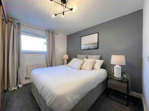 a bedroom with a large white bed and a window at Beautiful Hatfield 2 Bedroom Apartment FREE Gated Parking - Modern Stylish - Business Park, Hertforshire University, St Albans, Welwyn Garden City, Luton Airport, Harry Potter Studio Tour in Hatfield