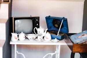 una mesa con TV y algunas tazas y tazas de té en Pousada Chalés do Toque, en São Miguel dos Milagres