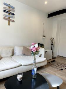 una sala de estar con un sofá blanco y una mesa con flores en una botella. en VILLA GABY~ 2 pers ~ Hypercentre, en Pau