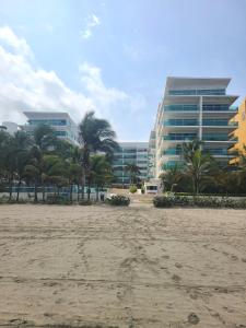 a beach with palm trees and a building at Apartamento Delux Morros-Tolusa in Cartagena de Indias