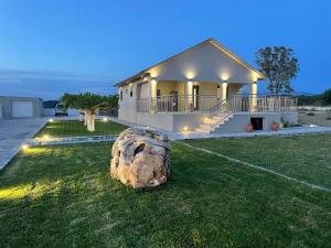 a large rock sitting in the grass in front of a house at Villa Vrahinari in Kounopetra