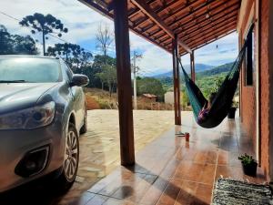 ein neben einem Haus mit einer Hängematte geparktes Auto in der Unterkunft Casa Amantes da Serra Ibitipoca - Satisfação Garantida in Conceição da Ibitipoca + 41 Fotos