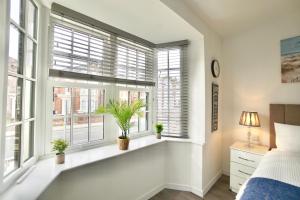 a bedroom with white walls and windows with potted plants at Luxury Flats in Southsea Portsmouth in Portsmouth