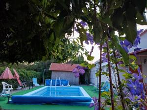 a swimming pool in a yard with purple flowers at Roxana vendégház in Szilvásvárad