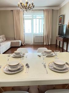 una mesa de comedor blanca con platos y cubiertos en "3-Bedroom Charming Apartment in Central Almaty", en Almaty