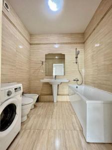 y baño con lavabo, aseo y lavadora. en "3-Bedroom Charming Apartment in Central Almaty", en Almaty