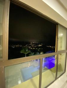 a window with a view of a city at night at Apartamento Alto da Serra Villas in Bananeiras