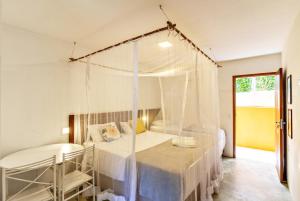 a bedroom with a canopy bed with a table and a chair at Pousada Imperador do Espelho in Praia do Espelho