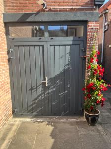 een grijze garagedeur met bloemen in een pot bij Appartement 4 Seasons Katwijk aan Zee in Katwijk aan Zee