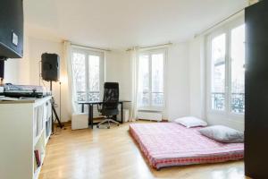 um quarto com uma cama, uma secretária e janelas em Appartement Paris Centre Vavin em Paris
