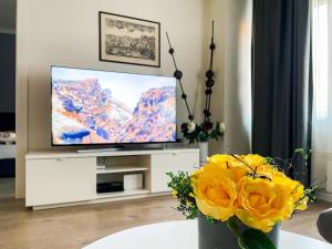 a living room with a television and a vase of yellow flowers at Point Rijeka in Rijeka