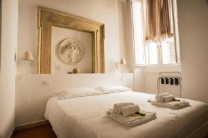 - une chambre blanche avec un lit et des serviettes dans l'établissement Flowers Apartments, à Rome