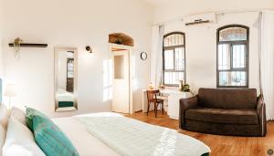 a bedroom with a bed and a couch and a chair at Maim Haim Tzfat - Boutique Suites Prime location Old City Tzfat in Safed