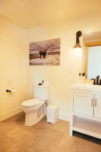 a bathroom with a toilet and a picture of a cow at The Lodge at 58* North in King Salmon