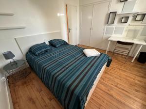ein Schlafzimmer mit einem großen Bett und einer gestreiften Decke in der Unterkunft Villa La Libellule Grand Jardin et Parking Privé in Toulouse