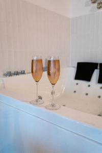 two wine glasses sitting on top of a bath tub at Bali Serenity Balnéo et lit rond in Lagnieu