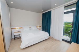 1 dormitorio con cama blanca y ventana grande en Ritsa Resort en Ureki
