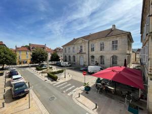 a building with a red umbrella in front of a street at Appartement La Tour in Vesoul
