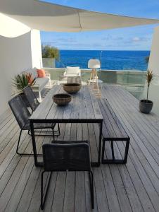 eine Holzterrasse mit einem Tisch, Stühlen und Meerblick in der Unterkunft Barrocas Villas Azores in São Roque