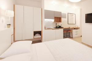 a white bedroom with a white bed and a kitchen at House Mateja Unije in Unije