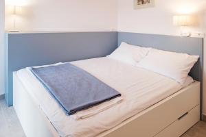 a bed with white sheets and a blue wall at House Mateja Unije in Unije
