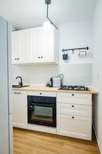uma cozinha com armários brancos e um forno de fogão preto em Modern studio D-va N em Zalău