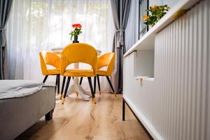 a dining room with yellow chairs and a table at Modern studio D-va N in Zalău +31 photos