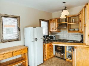 a kitchen with a white refrigerator and wooden cabinets at El Refugio de Montaña in San Martín de los Andes