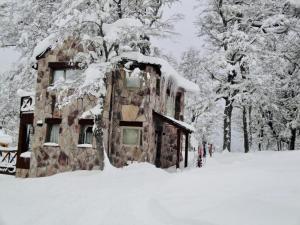 un bâtiment recouvert de neige avec des arbres en arrière-plan dans l'établissement El Refugio de Montaña, à San Martín de los Andes