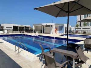 a swimming pool with a table and an umbrella at Apto con excelente Ubicación. in Barranquilla