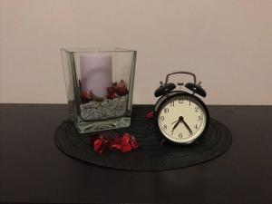 a clock sitting on a table next to a glass vase at Appartamento Elegante, Romantico e Riservato in Palazzolo dello Stella