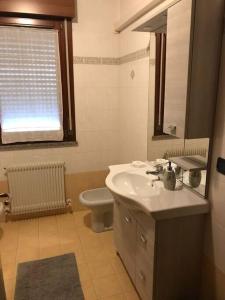 a bathroom with a sink and a toilet and a window at Appartamento Elegante, Romantico e Riservato in Palazzolo dello Stella