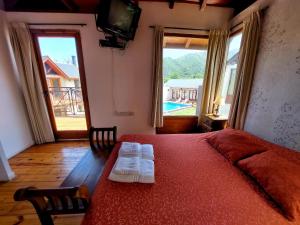 a bedroom with a red bed with two towels on it at Cabañas Ayres del Lago 2 in Potrero de los Funes