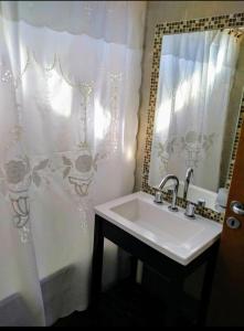 a bathroom with a sink and a shower curtain at Cabañas Ayres del Lago 2 in Potrero de los Funes