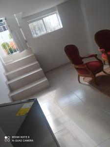 uma sala de estar com duas cadeiras e uma escada em Apartamento la 20 em Pereira