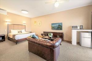 a hotel room with a bed and a leather couch at Eltham Gateway Hotel & Conference Centre in Eltham