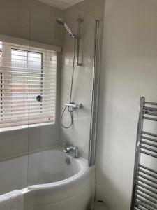 a bathroom with a bath tub and a shower at Charming 3 Bed Home For Family or Business Stays, Great Location, FREE Parking, Park Views, Sleeps 5! in Ashford