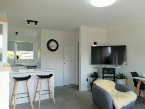 a kitchen with a counter and stools and a tv at Centre Takapuna 2 Beds & Garage & Netflix in Auckland