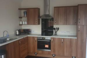 a kitchen with wooden cabinets and a stove top oven at New modern self contained Cottage in Delabole