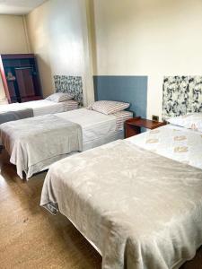 a room with three beds with white sheets at Kicker House in Puerto Baquerizo Moreno