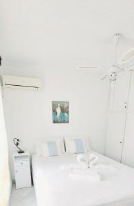 Un dormitorio blanco con una cama blanca y una foto en la pared en By the sea en Andros