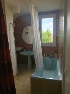 een badkamer met een bad, een wastafel en een raam bij Ker Anna in Athis-Mons