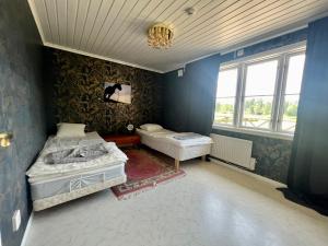 2 camas en una habitación con paredes y ventanas azules en Idylliskt hus med sjöutsikt., en Östhammar