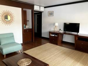ein Wohnzimmer mit einem TV, einem Stuhl und einem Tisch in der Unterkunft Tahiti Lafayette Beach Lodge in Arue