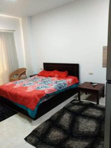 a bedroom with a bed with red pillows and a table at Al Makramia compound in Hurghada