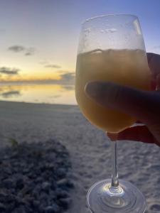 a hand holding a glass of wine on the beach at Rarotonga Villas Absolute Beachfront in Arorangi