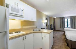 a kitchen with white cabinets and a room with a bed at Extended Stay America Suites - San Diego - Carlsbad Village by the Sea in Carlsbad